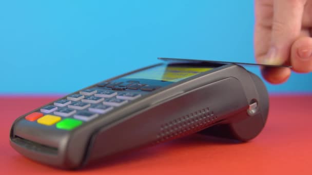 Paiement sans contact avec carte de crédit et terminal en gros plan sur fond couleur — Video