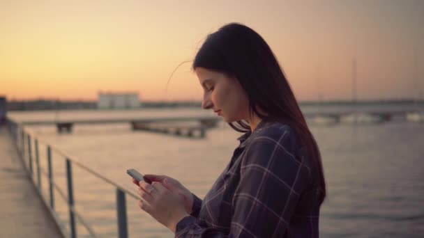 Mujer atractiva usando teléfono inteligente caminando en el muelle, blogger charlando al aire libre — Vídeo de stock