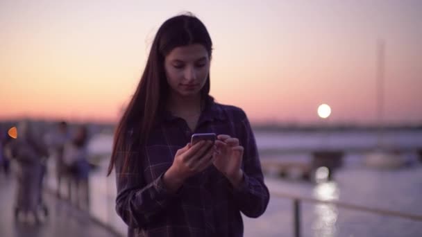 Kvinna promenader på gatan och använda smartphone, kväll natt stadsljus — Stockvideo