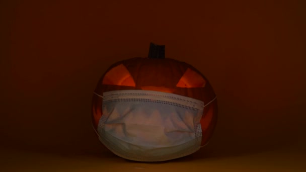 Тыква на Хэллоуин в защитной маске, светящийся Джек Фонарь, карантин Ковид-19 — стоковое видео