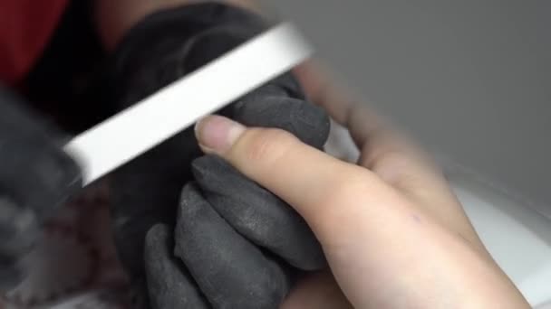 Manikúra pilník povelivaet klientské nehty. V černých rukavicích. 4K — Stock video