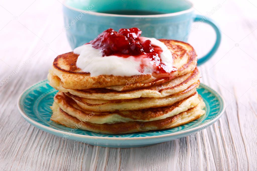 Buttermilk pancakes with yogurt and jam on blue plate
