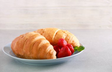 Kruvasan plaka, ahşap arka plan üzerinde çilek ile