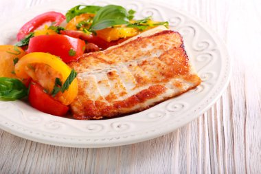 Plaka üzerinde kızarmış beyaz balık ve domates salatası