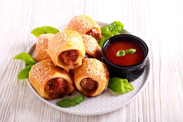 Mini sausage rolls with sesame on top, on plate