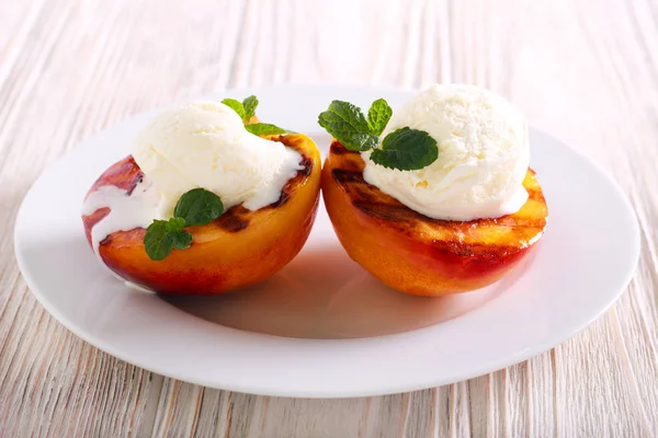 Grilled peaches with ice cream on plate
