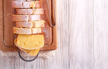 Ahşap tahta üzerinde şeker, krema ile kek, dilimlenmiş