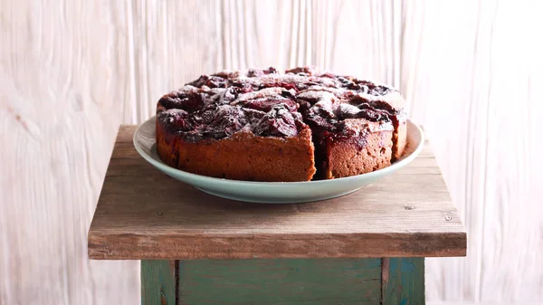 Spicy chocolate plum cake on plate over wooden background
