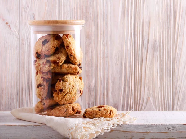 Oat and raisin cookies in a jar over wooden background