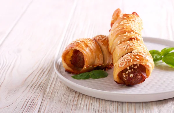 Sausage rolls with sesame on top, on plate