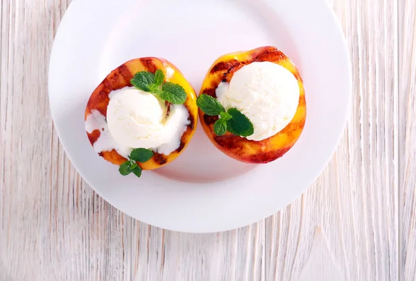 Grilled peaches with ice cream on plate