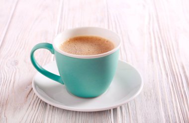 Ahşap masa üzerinde bir fincan sütlü kahve