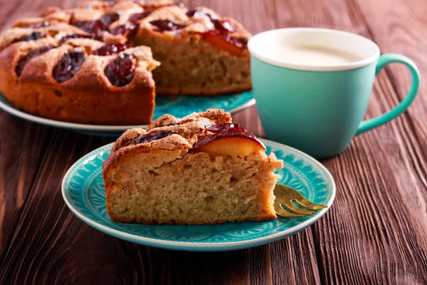 Plum cake, sliced on plate and cup of coffee