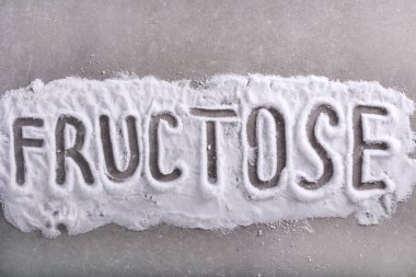Fructose word written in fructose powder over grey background clipart