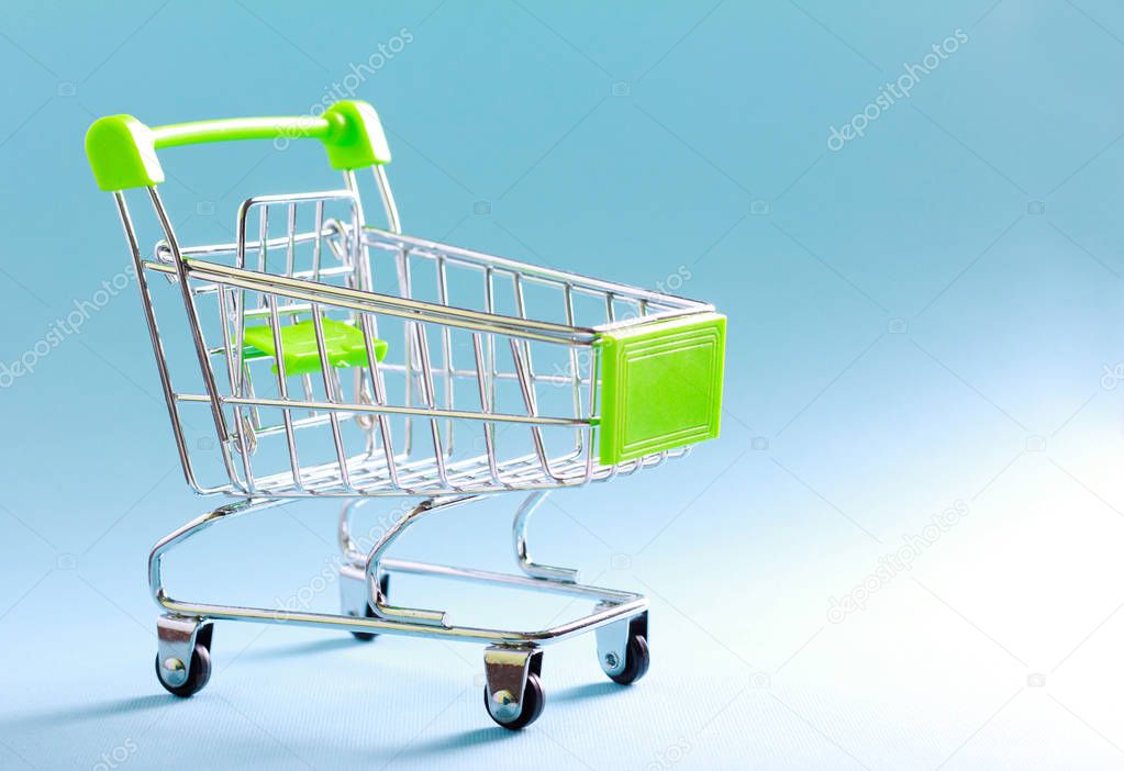 Empty mini shopping cart over blue background