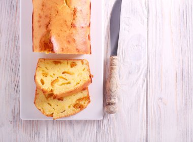 Ahşap masa üzerinde tabağa dilimlenmiş turuncu kek