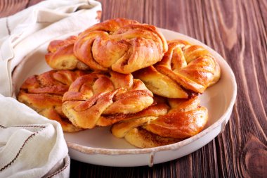 Ahşap arka plan üzerinde plaka üzerinde tarçınlı çörek