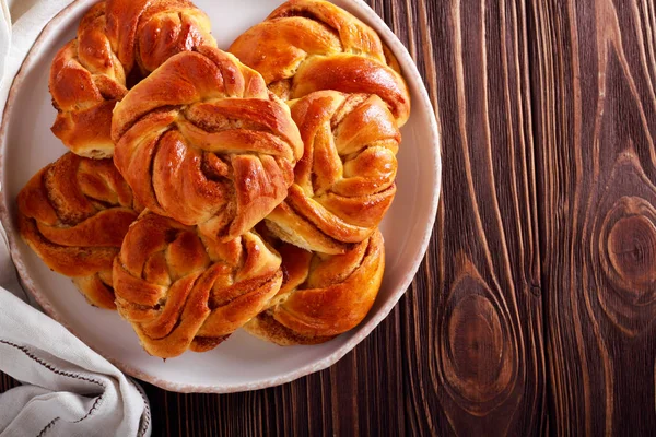 Ahşap arka plan üzerinde plaka üzerinde tarçınlı çörek