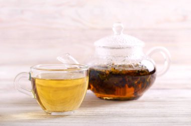 Ahşap arka plan üzerinde bir fincan sıcak bitkisel çay dökme