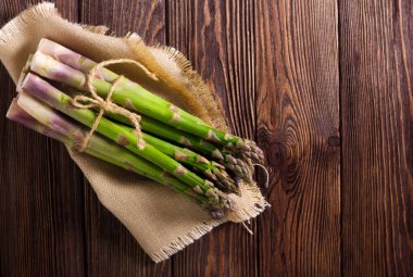 Ahşap arka planda bir sürü taze çiğ kuşkonmaz.