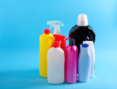 Mavi arkaplan üzerinde evde kullanılan renkli plastik şişelerin seçimi