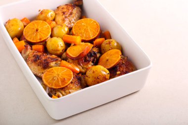 Havuç, patates ve portakalla pişirilmiş tavuk butları.