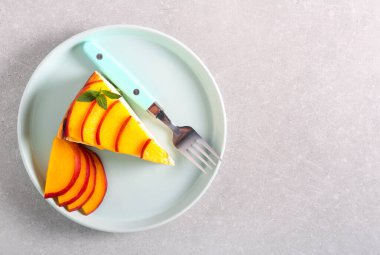 Nektarin soslu bir dilim cheesecake, tabakta servis edilir.