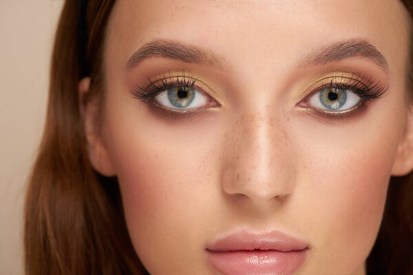 close-up of a pretty girls face with beautiful big blue eyes, big lashes and eyebrows
