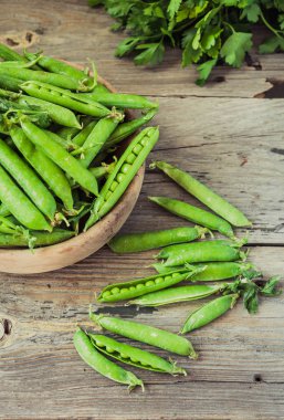 Yeşil bezelye POD üzerinde gri bir ahşap masa. Vegetables.Detox diyet ve yeşil yaz gıda kavramı. Seçici odak.