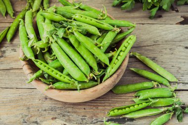 Yeşil bezelye POD üzerinde gri bir ahşap masa. Vegetables.Detox diyet ve yeşil yaz gıda kavramı. Üstten görünüm.