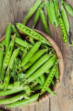 Yeşil bezelye POD üzerinde gri bir ahşap masa. Vegetables.Detox diyet ve yeşil yaz gıda kavramı. Seçici odak. Üstten görünüm.