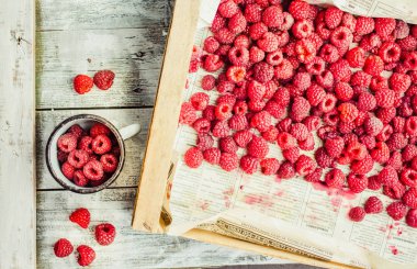 Mavi ahşap bir masa üzerinde bir kutu içinde kırmızı ahududu. Bir demir mug içinde taze çilek. Detoks Diyet ve yaz yiyecek konsepti