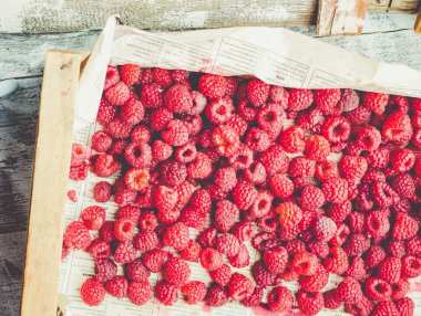 Mavi ahşap bir masa üzerinde bir kutu içinde kırmızı ahududu. Taze çilek. Detoks Diyet ve yaz gıda kavramı. Tonlama.