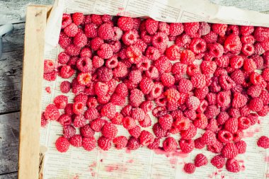 Mavi ahşap bir masa üzerinde bir kutu içinde kırmızı ahududu. Taze çilek. Detoks Diyet ve yaz yiyecek konsepti