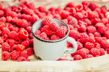 Mavi ahşap bir masa üzerinde bir kutu içinde kırmızı ahududu. Taze çilek. Sağlıklı ve ham antioksidan gıda kavramı.