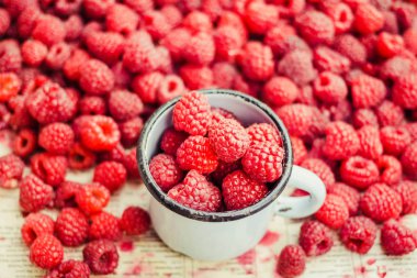 Mavi ahşap bir masa üzerinde bir kutu içinde kırmızı ahududu. Taze çilek yığını. Detoks Diyet ve yaz gıda kavramı. Portre.