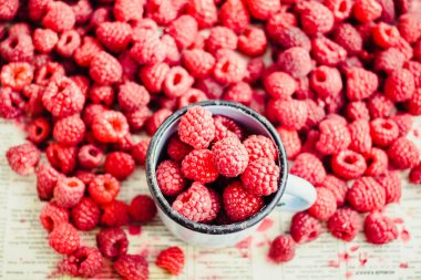 Mavi ahşap bir masa üzerinde bir kutu içinde kırmızı ahududu. Yığın bir demir mug içinde taze çilek. Detoks Diyet ve yaz gıda kavramı. Portre.