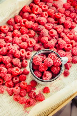 Mavi ahşap bir masa üzerinde bir kutu içinde kırmızı ahududu. Taze çilek. Sağlıklı ve ham antioksidan gıda kavramı. Üstten görünüm.
