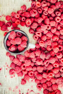 Mavi ahşap bir masa üzerinde bir kutu içinde kırmızı ahududu. Bir demir mug içinde taze çilek. Detoks Diyet ve yaz gıda kavramı. Üstten görünüm.