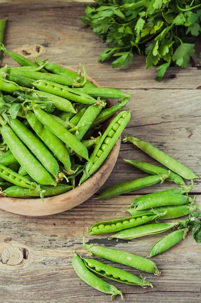 Yeşil bezelye POD üzerinde gri bir ahşap masa. Vegetables.Detox diyet ve yeşil yaz gıda kavramı. Seçici odak.
