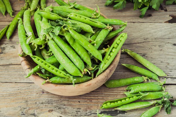 Yeşil bezelye POD üzerinde gri bir ahşap masa. Vegetables.Detox diyet ve yeşil yaz gıda kavramı. Üstten görünüm.
