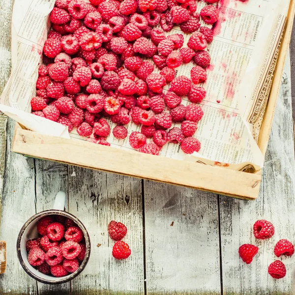 Red raspberries in a box on a blue wooden table. Fresh berries.Detox diet and summer food concept.Instagram size.