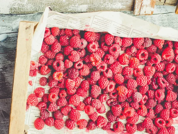 Mavi ahşap bir masa üzerinde bir kutu içinde kırmızı ahududu. Taze çilek. Detoks Diyet ve yaz gıda kavramı. Tonlama.