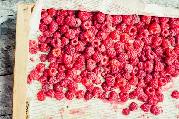 Mavi ahşap bir masa üzerinde bir kutu içinde kırmızı ahududu. Taze çilek. Detoks Diyet ve yaz yiyecek konsepti