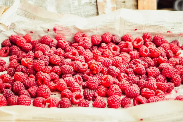 Mavi ahşap bir masa üzerinde bir kutu içinde kırmızı ahududu. Taze çilek. Sağlıklı ve ham antioksidan gıda kavramı.