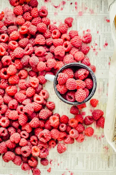 Mavi ahşap bir masa üzerinde bir kutu içinde kırmızı ahududu. Bir demir mug içinde taze çilek. Detoks Diyet ve yaz gıda kavramı. Üstten görünüm.