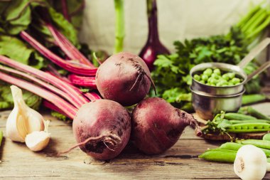 Organik genç pancar, Yeşiller, sarımsak ahşap arka plan üzerinde. Sonbahar taze sebze. Seçici odak. Sağlıklı ve ham antioksidan gıda kavramı.