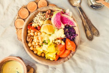 Bir dengeli öğle/akşam yemeği - çok renkli sebze, baharatlı fasulye (nohut), kurutulmuş domates, limon, fındık, kimchi zerdeçal ahşap yemekler ile