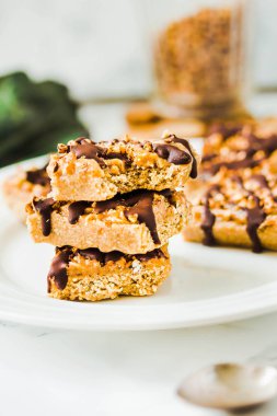 Granola bar with date caramel and chocolate. Healthy sweet dessert snack. Cereal granola bar with nuts, fruit and berries on a white marble table.