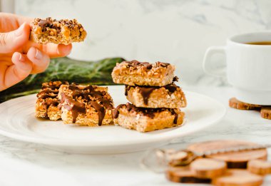 Organik Granola bar pasta. Sağlıklı kahvaltı ve snack. Beyaz masa arka plan... Yeme işlemi. Genç bir kadın elinde. Sağlıklı kahvaltı.